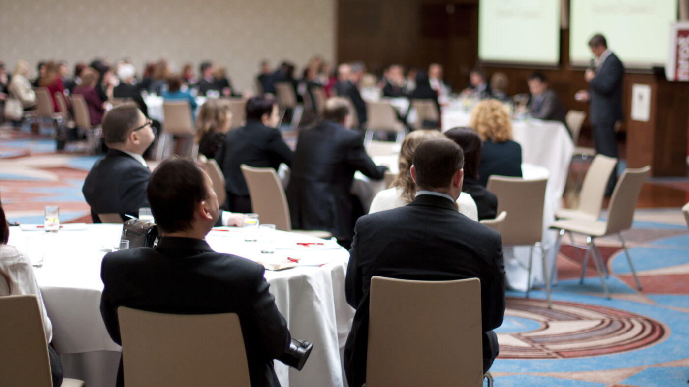 Business conference with attendees sitting at tables.